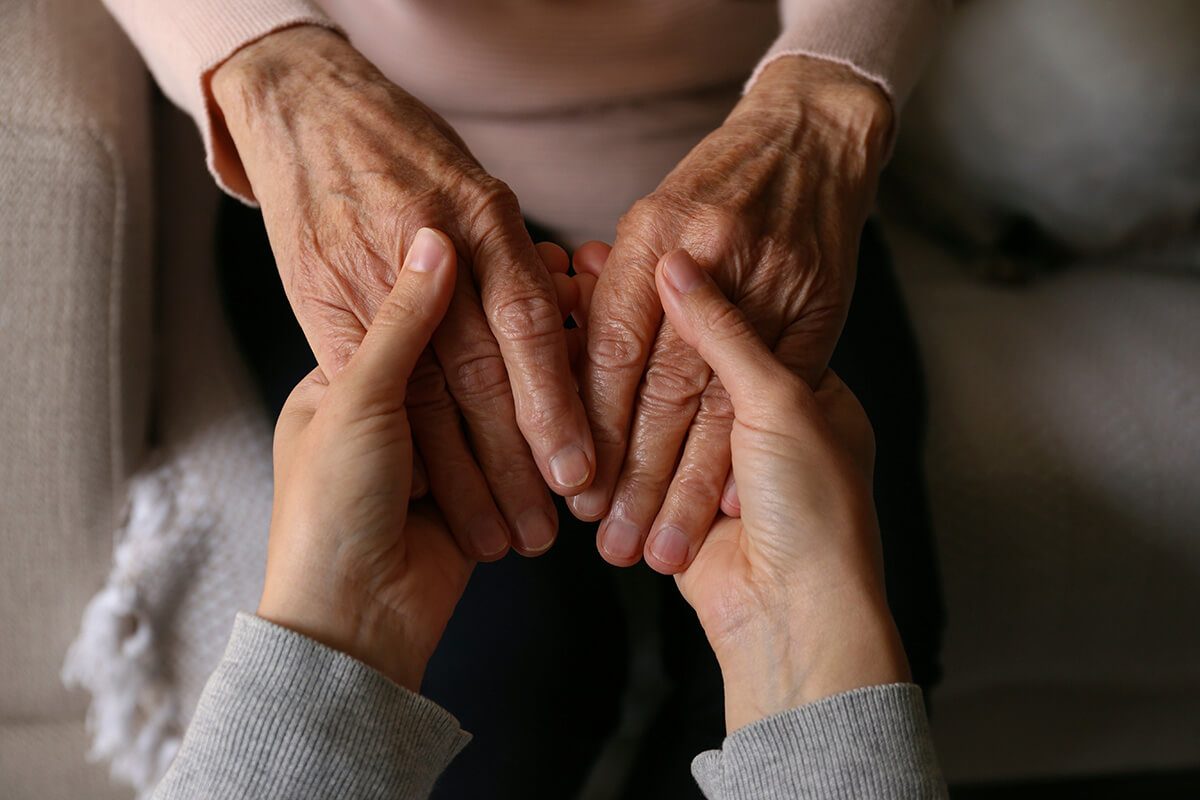 Two people holding hands in a moment of reassurance